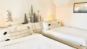 Ein Schlafzimmer mit zwei Einzelbetten, einem Nachttisch, einer kleinen Zimmerpflanze und einer Wandleuchte.
