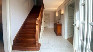 Un escalier menant à un palier où se trouvent une porte, un petit meuble et un miroir.