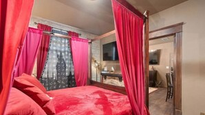 A bedroom with a bed, red curtains, a TV, and a mirror. - Harry's Hangout at Legacy Dunes | Sage Vacations (Kissimmee)