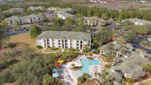 A resort with multiple buildings, a swimming pool, and surrounding greenery. - Harry's Hangout at Legacy Dunes | Sage Vacations (Kissimmee)