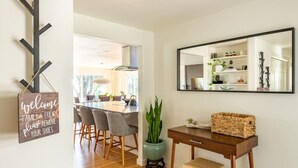 Een moderne woonkamer met een eethoek, een grote spiegel en een welkomstbord.