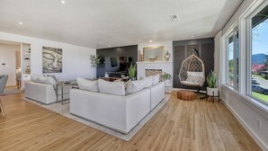 Un salon moderne avec un canapé blanc, un fauteuil suspendu et une cheminée.