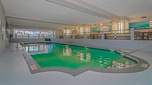 Ein Hallenbad mit klarem Wasser, umgeben von einer Poolterrasse und einer Glaswand.