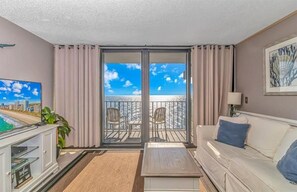 Una sala de estar con balcón con vistas a la playa.