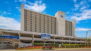 Ein großes Hotelgebäude mit mehreren Etagen und Balkonen, eine Schilder mit der Aufschrift 'Royal Garden Resort' und eine Tiefgarage darunter.