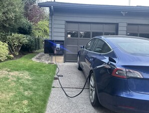 A blue car parked in front of a building with a garage door.