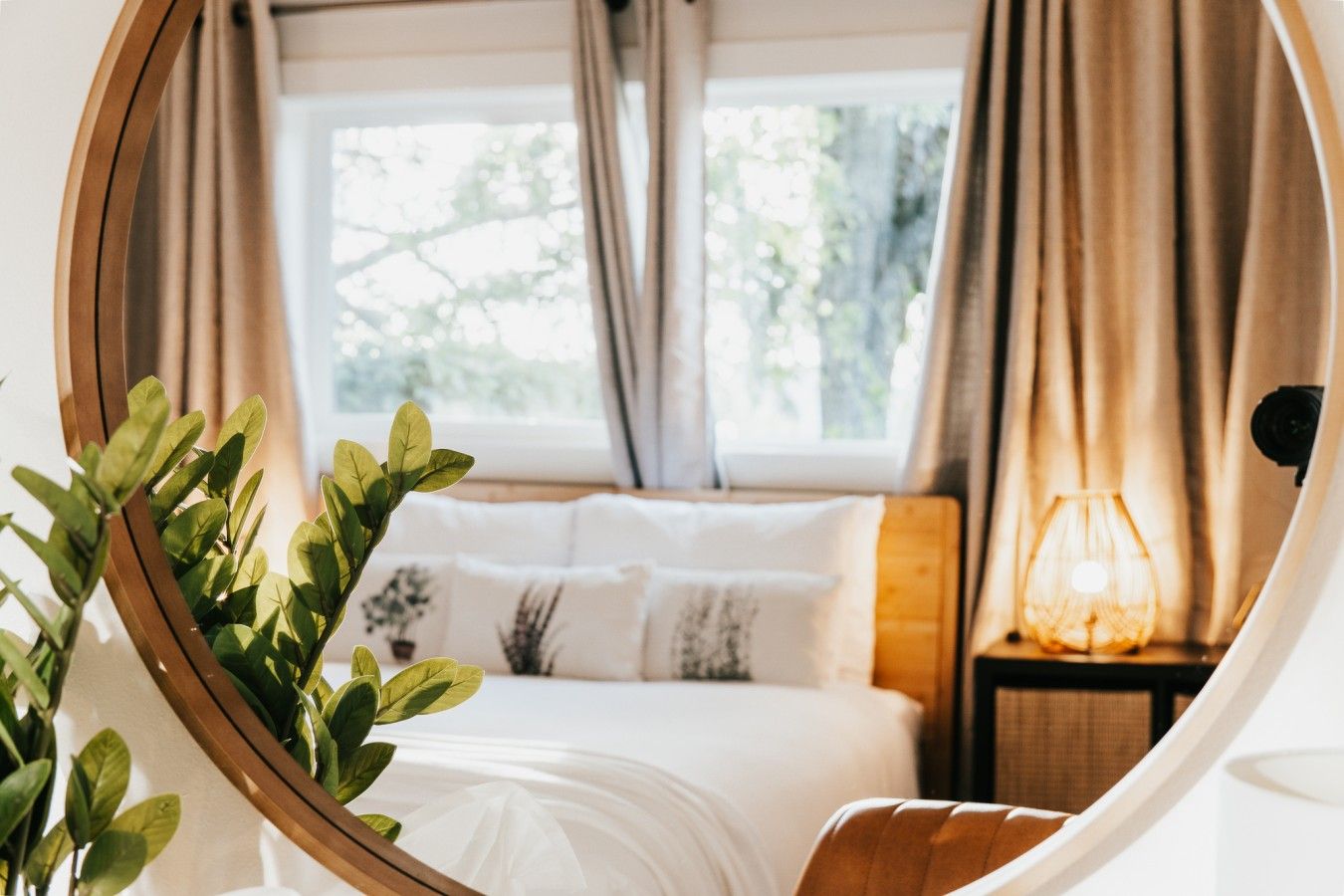 A bedroom with a bed, a nightstand, a lamp, and a window with curtains.