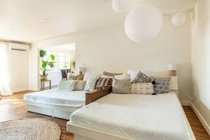 A modern bedroom with two beds, a large window, and a view of greenery outside. - Zen Haus suite A&B · Luxe Spacious Retreat, UofO 1 mile, KING beds, soaking tub (Eugene)