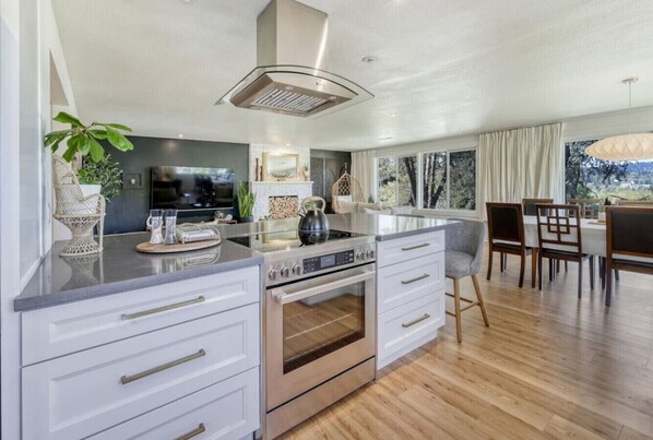 A modern kitchen with a central island, built-in oven, and a dining area with a view. - Zen Haus suite A&B · Luxe Spacious Retreat, UofO 1 mile, KING beds, soaking tub (Eugene)