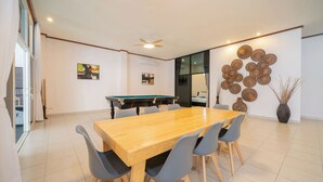 A modern room with a pool table, a dining table with chairs, and a large decorative wall piece.