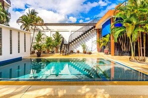 A swimming pool with a clear blue water surface, surrounded by potted plants and palm trees. - Jungceylon Villa in Patong by Lofty (Patong)