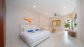A spacious bedroom with a large bed, a ceiling fan, and a view of the outdoor area.