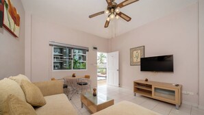 A living room with a sofa, coffee table, TV, and a ceiling fan.
