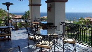 Un patio exterior con mesas y sillas, un adorno colgante en forma de estrella y vistas al océano.
