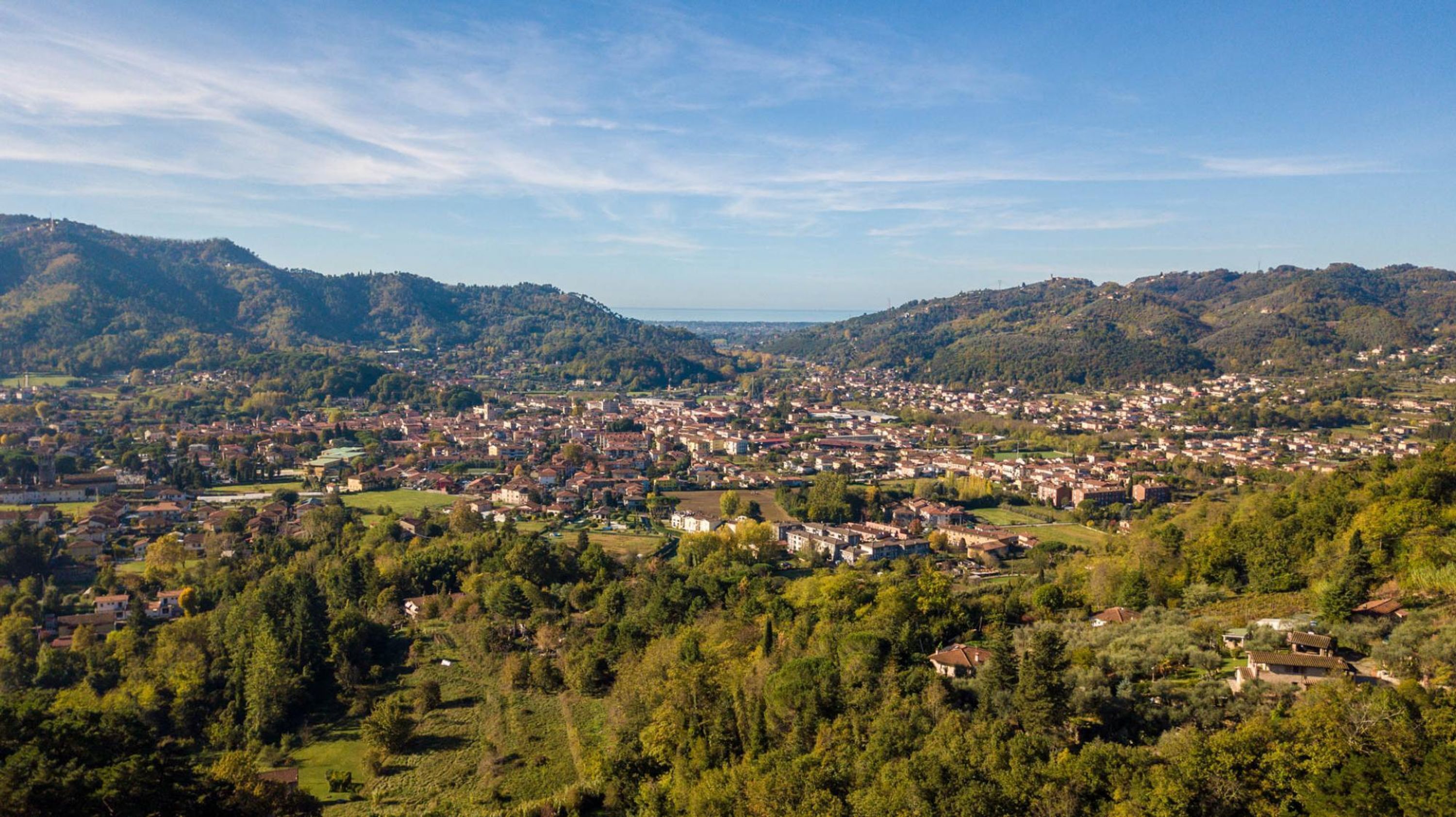 A town nestled in a valley with a mix of residential and commercial buildings, surrounded by hills and greenery.