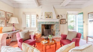 Un salon chaleureux avec deux fauteuils rouges, une table basse en bois et une cheminée ornée de carreaux décoratifs.