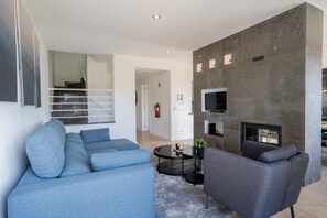 Ein modernes Wohnzimmer mit einem grauen Sofa, einem grauen Sessel, einem runden Couchtisch und einem Flachbildfernseher, der an einer grauen Wand angebracht ist.