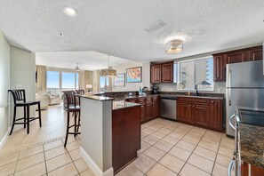 Una cocina amplia con una isla central, armarios de madera oscura y un refrigerador grande.