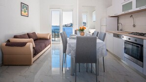 A modern apartment with a dining area, kitchen, and a balcony with a view. - Apartments Happy Holiday (Rogoznica)