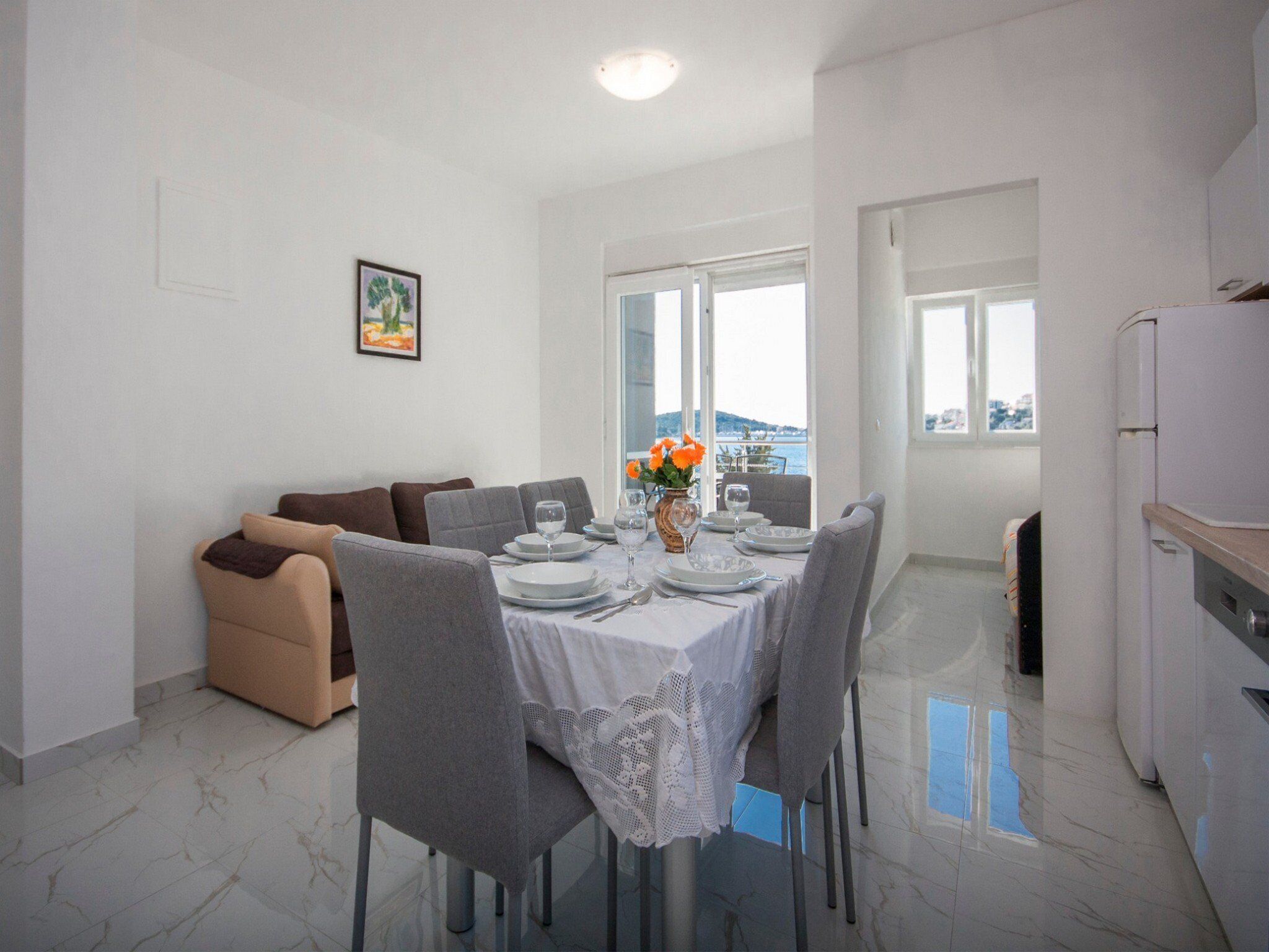 A dining area with a table set for four, a sofa, and a view of the sea.