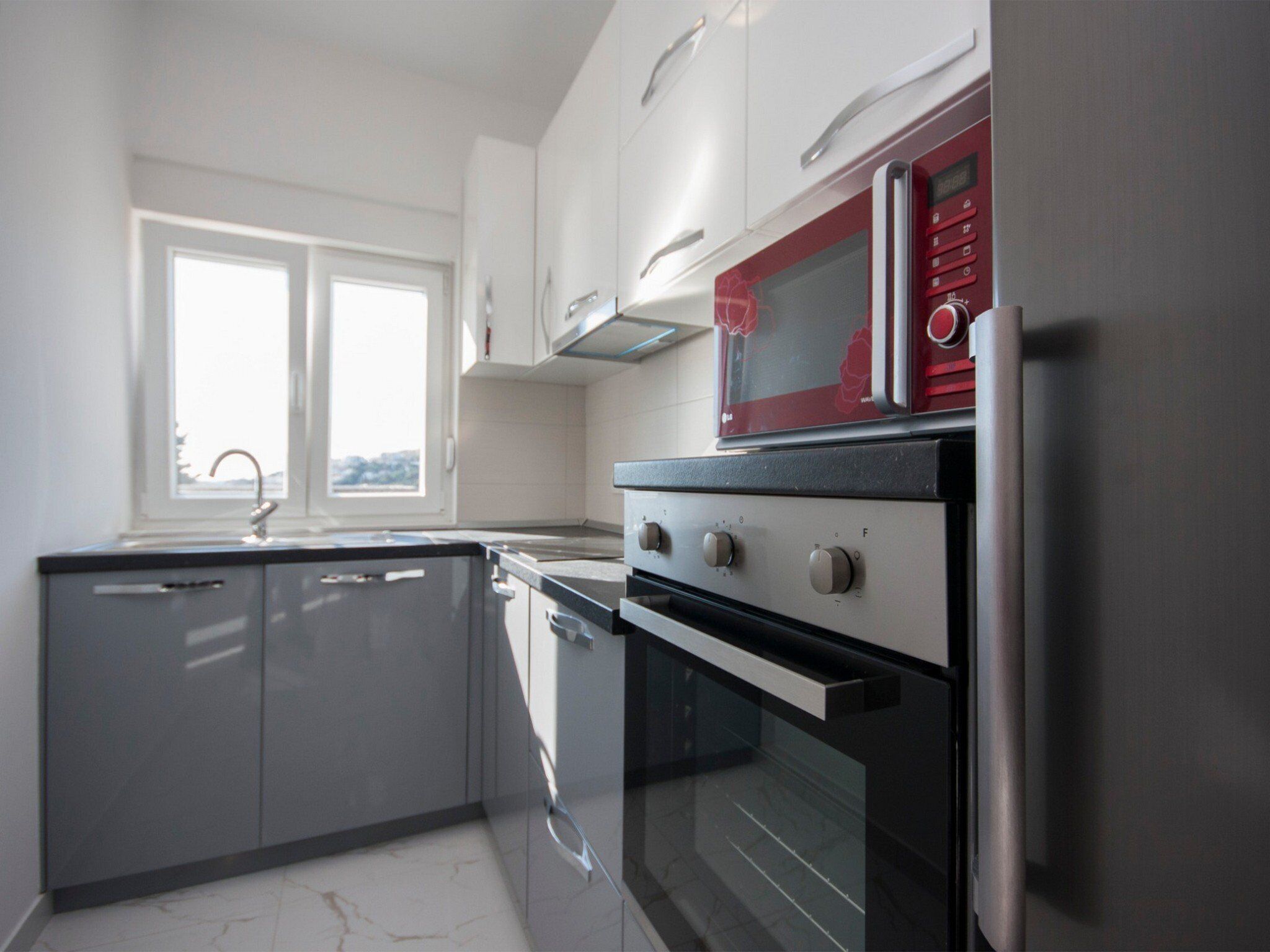 A modern kitchen with a built-in oven, a microwave, and a stainless steel refrigerator.