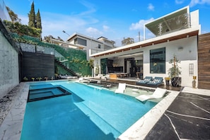 A modern house with a swimming pool, outdoor seating, and a large window overlooking the pool. - Luxury Villa (Los Angeles)