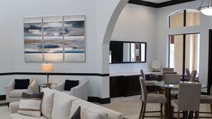 A modern lobby with a sofa, chairs, a dining area, and a large abstract painting on the wall. - Beautiful Naples Retreat! (Naples)