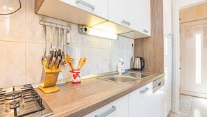A modern kitchen with white cabinets, a wooden countertop, a gas stove, a coffee maker, and a kettle.
