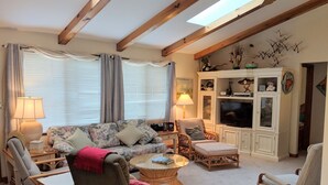 Een woonkamer met een bank, stoelen, een salontafel, een televisie en een kast.
