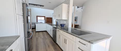 A modern kitchen with white cabinetry, a central island, and a built-in oven.