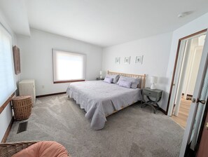 Une chambre à coucher avec un lit, des tables de chevet, une fenêtre et une porte.
