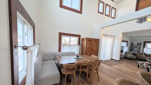 A spacious living area with a dining table, chairs, a sofa, and a wooden cabinet. - Canalfront Home in South Bethany - new kitchen! (Bethany Beach)
