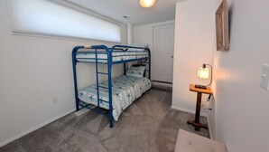 A room with bunk beds, a small table with a lamp, and a door. - Canalfront Home in South Bethany - new kitchen! (Bethany Beach)