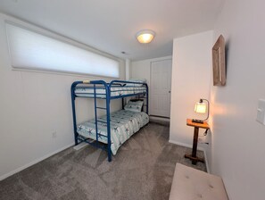 A room with bunk beds, a small table with a lamp, and a door. - Canalfront Home in South Bethany - new kitchen! (Bethany Beach)