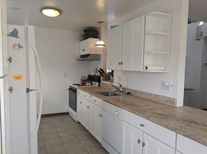 Kitchen features an oven, stainless steel range hood, and a single sink with modern faucet.