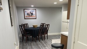 Un coin repas avec une table et des chaises, une poubelle et un tableau encadré au mur.