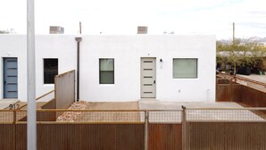 A modern building with a white facade, numbered 912, featuring a small window, a door, and a visible staircase leading to an upper level.