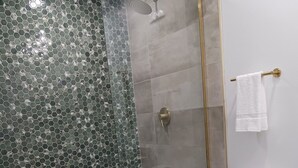A bathroom with a glass-enclosed shower, a white toilet, and a marble countertop.
