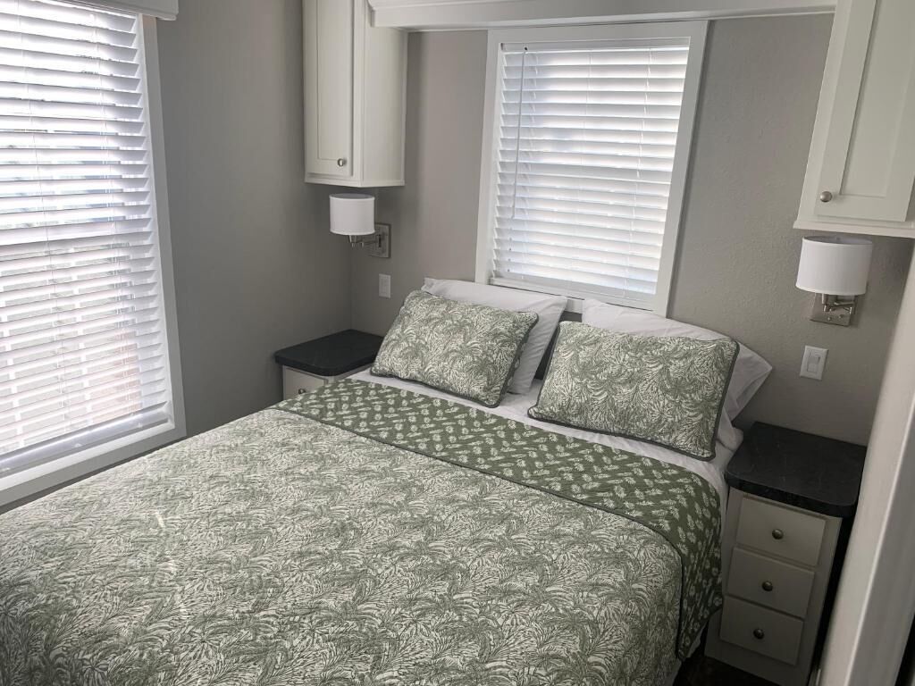 A bedroom with a bed, two nightstands, a dresser, and a window with blinds.