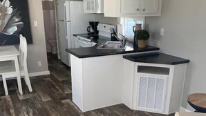 A modern kitchen with white cabinets, a black countertop, and a wooden floor. - Caribbean Shores Vacation Rentals (Jensen Beach)