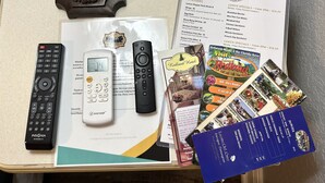 A table with various items including a remote control, a hotel brochure, a menu, and a brochure for a Florida Keys tour. - Entrance to the Florida Keys, The Historic Hotel Redland (Homestead)