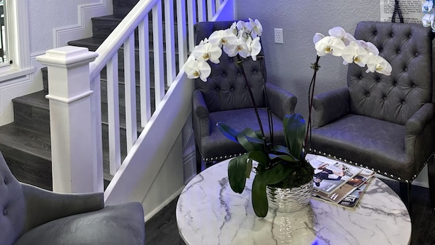 A hotel lobby with a staircase, a neon sign reading "The Hotel Redmond," a chandelier, and a seating area with a plant on a marble table. - Entrance to the Florida Keys, The Historic Hotel Redland (Homestead)