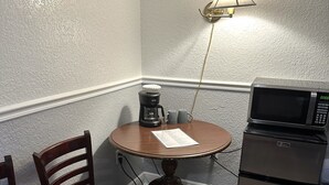 A small dining area with a table, two chairs, a coffee maker, a microwave, and a lamp. - Entrance to the Florida Keys, The Historic Hotel Redland (Homestead)