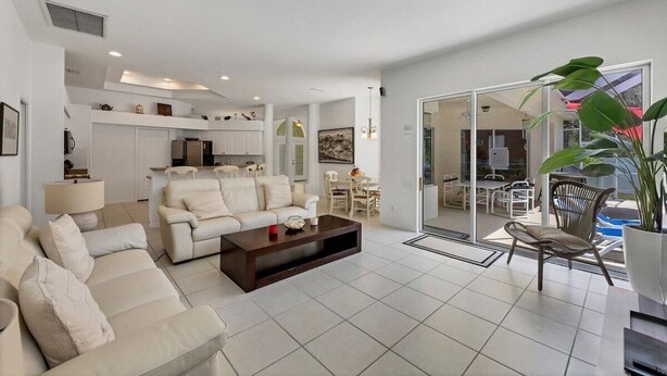 A spacious living room with a sofa, coffee table, and a dining area with chairs and a table. - Tipsy Turtle - Beautifully Landscaped Secluded pool and spa home (Venice)