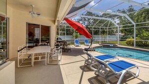 A covered outdoor area with a pool, lounge chairs, and a table. - Tipsy Turtle - Beautifully Landscaped Secluded pool and spa home (Venice)