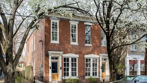 A two-story brick building with a traditional facade, large windows, and a car parked in front.