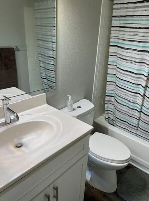 Bathroom features a sink, mirror, and toilet, with a striped wallpaper and a towel hanging on the wall.