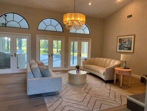 Relax in this stylish living room with a large sofa, round coffee table, and elegant chandelier.