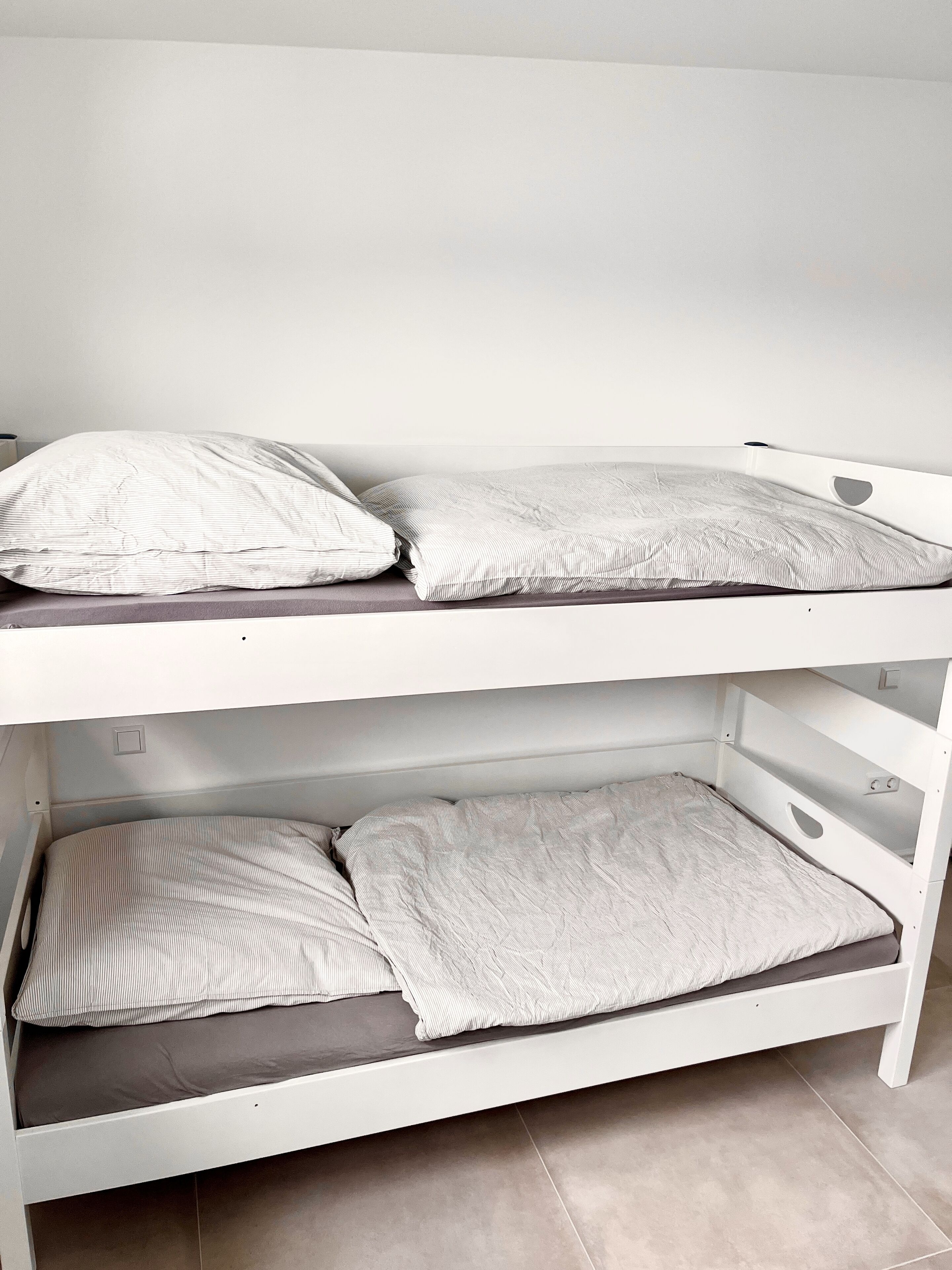 Een stapelbed met twee niveaus, elk voorzien van een kussen en een matras.