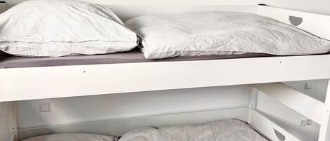 Een stapelbed met twee niveaus, elk voorzien van een kussen en een matras.